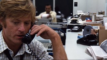 Movie still from “All the President's Men” (1976), directed by Alan J. Pakula – A man sitting at a desk talking on a phone; Close Up shot, Low angle