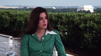 Movie still from “All the President's Men” (1976), directed by Alan J. Pakula – A woman in a green dress sitting on a bench; Medium shot, Over the shoulder angle