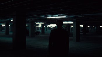 Movie still from “All the President's Men” (1976), directed by Alan J. Pakula – A man standing in a dark room in a parking garage; Wide shot, Over the shoulder angle