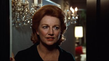 Movie still from “All the President's Men” (1976), directed by Alan J. Pakula – An older woman with red hair looking at the camera; Close Up shot, Over the shoulder angle
