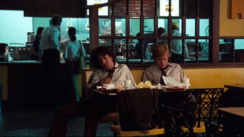 Movie still from “All the President's Men” (1976), directed by Alan J. Pakula – A couple of men sitting at a table with food; Wide shot, Over the shoulder angle