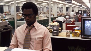 Movie still from “All the President's Men” (1976), directed by Alan J. Pakula – A man standing in an office with a tie around his neck; Medium shot, Low angle