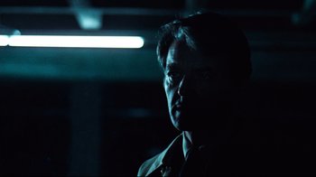 Movie still from “All the President's Men” (1976), directed by Alan J. Pakula – A man in a dark room looking at the camera; Close Up shot, Over the shoulder angle
