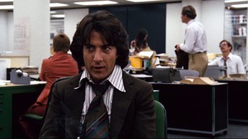 Movie still from “All the President's Men” (1976), directed by Alan J. Pakula – A man in a suit and tie in an office setting; Medium shot, Low angle