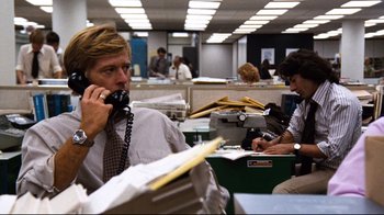 Movie still from “All the President's Men” (1976), directed by Alan J. Pakula – A man talking on a phone in an office cubicle; Medium shot, Over the shoulder angle