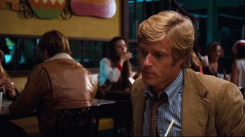 Movie still from “All the President's Men” (1976), directed by Alan J. Pakula – A person sitting at a table in a room; Medium shot, Over the shoulder angle
