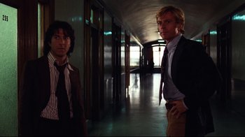 Movie still from “All the President's Men” (1976), directed by Alan J. Pakula – Two men standing in a hallway with one man wearing a suit and tie; Medium shot, Low angle