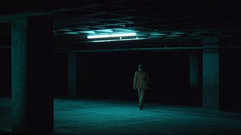A man walking in an empty parking garage at night