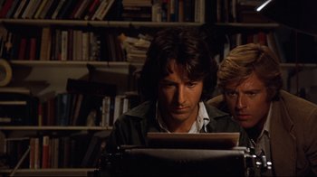 Movie still from “All the President's Men” (1976), directed by Alan J. Pakula – A man sitting next to another man in front of a book shelf; Medium shot, Low angle
