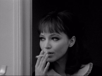 Movie still from “Alphaville” (1965), directed by Jean-Luc Godard – A black - and - white photo of a woman smoking a cigarette; Close Up shot, High angle