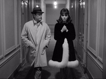 Movie still from “Alphaville” (1965), directed by Jean-Luc Godard – A man and a woman standing in a hallway; Medium shot, High angle