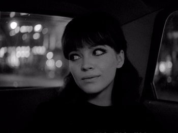 Movie still from “Alphaville” (1965), directed by Jean-Luc Godard – A black - and - white photo of a woman in a car; Close Up shot, High angle