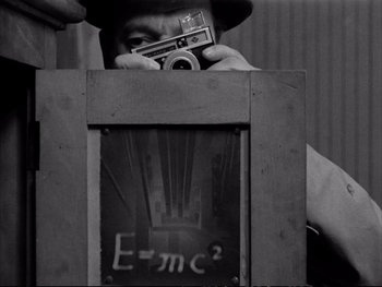 Movie still from “Alphaville” (1965), directed by Jean-Luc Godard – A man taking a picture of an equation on a wall; Extreme Close Up shot, Overhead angle