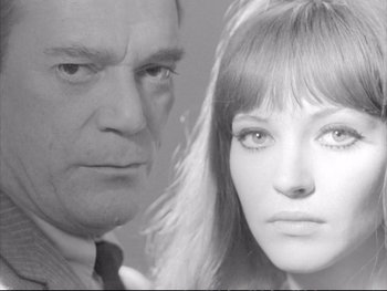 Movie still from “Alphaville” (1965), directed by Jean-Luc Godard – An older man and a younger woman looking at the camera; Close Up shot, Low angle