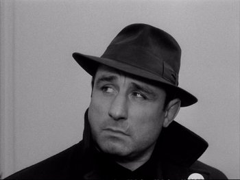 Movie still from “Alphaville” (1965), directed by Jean-Luc Godard – Black and white photograph of a man wearing a hat; Close Up shot, Low angle