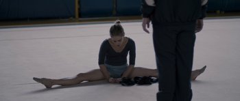 Movie still from “Alps” (2011), directed by Yorgos Lanthimos – A woman sitting on the ground with her legs crossed; Medium shot, High angle