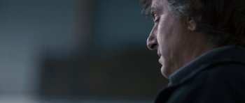 Movie still from “Alps” (2011), directed by Yorgos Lanthimos – A person's face in a dark room; Close Up shot, Over the shoulder angle