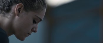 Movie still from “Alps” (2011), directed by Yorgos Lanthimos – A woman's face in a dark room; Close Up shot, Over the shoulder angle