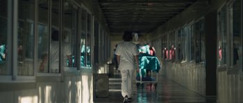 Movie still from “Alps” (2011), directed by Yorgos Lanthimos – A person walking down a hallway in a hospital; Extreme Wide shot, Low angle