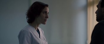 Movie still from “Alps” (2011), directed by Yorgos Lanthimos – A woman in a white lab coat looking to her left; Close Up shot, Over the shoulder angle
