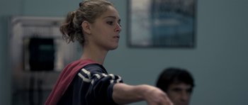 Movie still from “Alps” (2011), directed by Yorgos Lanthimos – A young woman is holding her hand out to someone in a room; Close Up shot, Over the shoulder angle