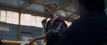 Movie still from “Alps” (2011), directed by Yorgos Lanthimos – A young woman is holding onto a rope in a gym; Close Up shot, Low angle