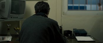 Movie still from “Alps” (2011), directed by Yorgos Lanthimos – A man sitting in front of a window with his back turned; Medium shot, Over the shoulder angle