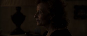Movie still from “Alps” (2011), directed by Yorgos Lanthimos – An older woman's face in the dark; Close Up shot, Over the shoulder angle