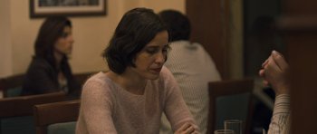 Movie still from “Alps” (2011), directed by Yorgos Lanthimos – A woman sitting at a table with a glass of water; Close Up shot, Over the shoulder angle
