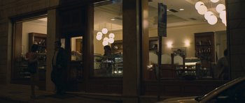 Movie still from “Alps” (2011), directed by Yorgos Lanthimos – A person standing in front of a store window at night; Wide shot, Over the shoulder angle