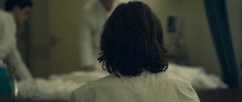 Movie still from “Alps” (2011), directed by Yorgos Lanthimos – A person with a white shirt is looking in the mirror; Close Up shot, Over the shoulder angle