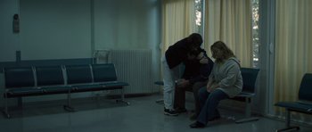 Movie still from “Alps” (2011), directed by Yorgos Lanthimos – A man and a woman sitting in a waiting room; Wide shot, Over the shoulder angle