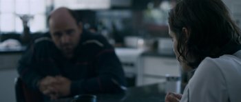 Movie still from “Alps” (2011), directed by Yorgos Lanthimos – Two people sitting at a table with a cup of coffee; Close Up shot, Over the shoulder angle