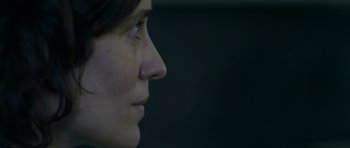 Movie still from “Alps” (2011), directed by Yorgos Lanthimos – A woman's face in a dark room; Extreme Close Up shot, Low angle