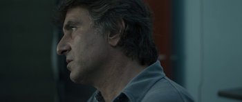 Movie still from “Alps” (2011), directed by Yorgos Lanthimos – A person wearing a gray shirt; Close Up shot, Low angle