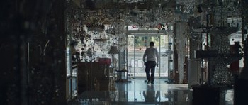 Movie still from “Alps” (2011), directed by Yorgos Lanthimos – A man walking in a room filled with chandeliers; Wide shot, High angle