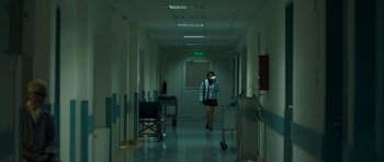 Movie still from “Alps” (2011), directed by Yorgos Lanthimos – A woman is walking down a hallway in a hospital; Wide shot, High angle