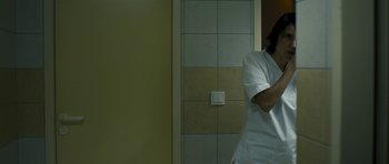 Movie still from “Alps” (2011), directed by Yorgos Lanthimos – A person standing in front of a bathroom mirror; Medium shot, Low angle