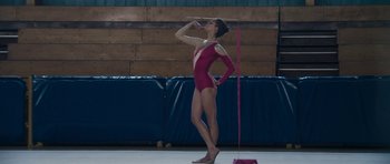 Movie still from “Alps” (2011), directed by Yorgos Lanthimos – A woman in a pink leotard is drinking water; Wide shot, Low angle