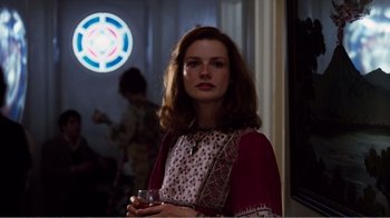 Movie still from “Altered States” (1980), directed by Ken Russell – A woman standing in front of a window holding a drink; Medium shot, Over the shoulder angle