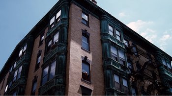 Movie still from “Altered States” (1980), directed by Ken Russell – A tall brick building with green trim and a fire escape; Extreme Wide shot, Low angle