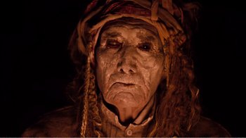 Movie still from “Altered States” (1980), directed by Ken Russell – An old man wearing a headdress and looking at the camera; Close Up shot, Overhead angle