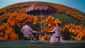 Movie still from “Altered States” (1980), directed by Ken Russell – Two people sitting at a table under an umbrella; Wide shot, High angle