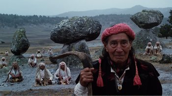 Movie still from “Altered States” (1980), directed by Ken Russell – An old man holding a stick in front of a group of people; Medium shot, Low angle