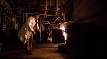 Movie still from “Altered States” (1980), directed by Ken Russell – A man in a white lab coat standing in front of an oven; Wide shot, Low angle