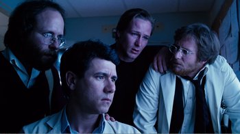 Movie still from “Altered States” (1980), directed by Ken Russell – A group of men standing next to each other in a room; Medium shot, Low angle