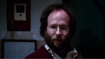 Movie still from “Altered States” (1980), directed by Ken Russell – A man with a beard wearing glasses and a red sweater; Close Up shot, Low angle