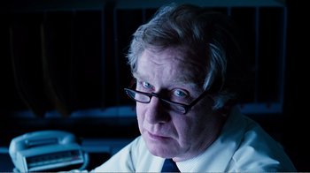 Movie still from “Altered States” (1980), directed by Ken Russell – An older man wearing glasses and a white shirt; Close Up shot, Over the shoulder angle