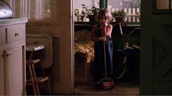 Movie still from “Altered States” (1980), directed by Ken Russell – A little girl standing in a room holding a toy; Medium shot, High angle