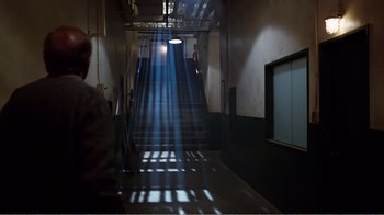 Movie still from “Altered States” (1980), directed by Ken Russell – A person is walking down a hallway with a light shining on them; Wide shot, Low angle